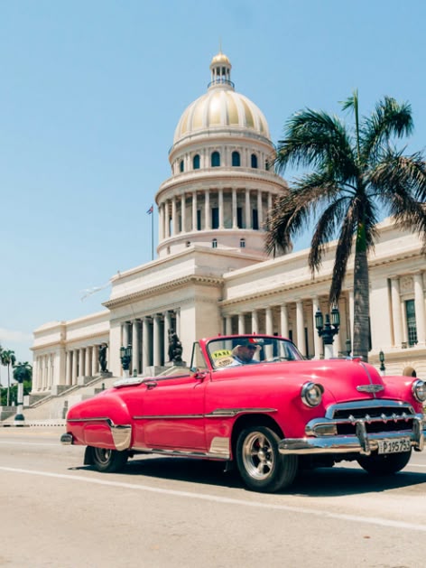 Klasyczny samochód przejeżdża przed budynkiem Kapitolu w Hawanie, Kuba, łącząc historyczny urok z tropikalnym klimatem miasta.